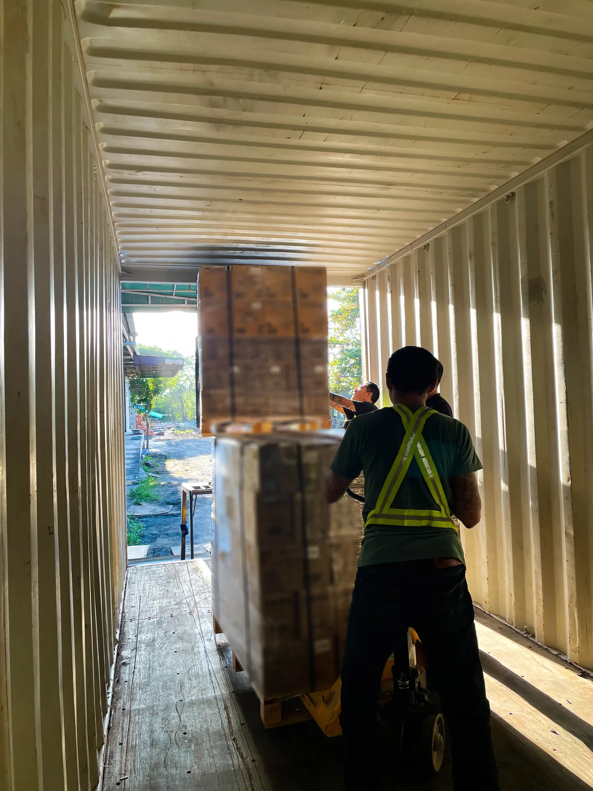 Workers moving palletised cargo inside a shipping container